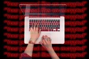 2. A person uses a laptop with “Your personal files are encrypted” written in black and highlighted in red over top.